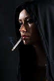 Young woman on a black background smoking a cigarette