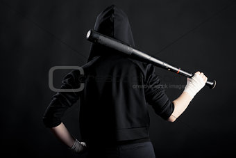 Young woman with a baseball bat. View from the back. hoodlum