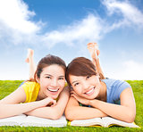 happy pretty students lying on the grassland with books