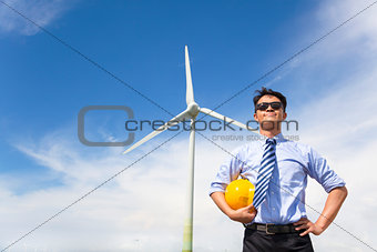 professional young engineer standing with wind generator 