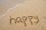 Happy word written on sandy the beach