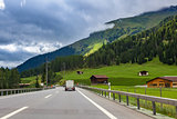 Highway along green fields and mountains in Switzerland.