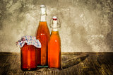 Bottles filled with yellow syrup and jam on kitchen table