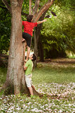 Two children helping and climbing on tree in park