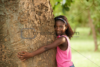 Portrait of black ecologist girl hugging tree and smiling
