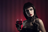 Dangerous sexy vampire girl with glass of wine or blood 