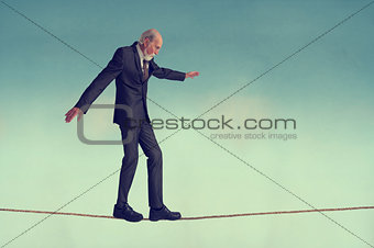 senior man walking a tightrope