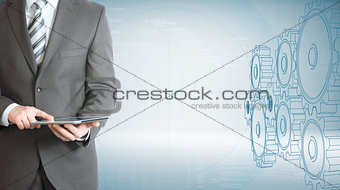 Businessman hold tablet pc. Gears and graphs