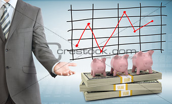 Businessman points hand on piggy banks and money