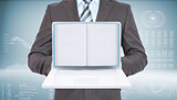 Businessman standing with open laptop and book