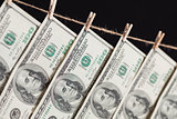 Hundred Dollar Bills Hanging From Clothesline on Dark Background