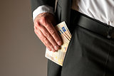 Businessman putting money in pocket