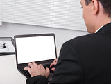 Rear view of businessman busy using laptop at office desk