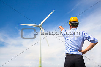  young engineer standing and point to wind generator 
