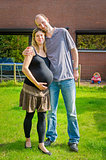 Couple with pregnant wife at garden in front of house