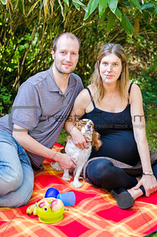Happy family with their dog and pregnant mothe rin park