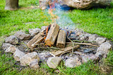 Firewood burning in fire with smoke surrounded by stones