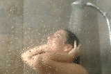 Portrait of a woman showering through the bath screen