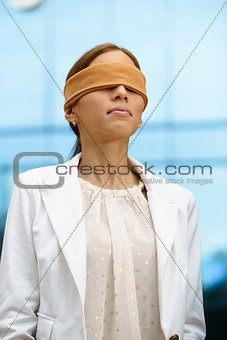 Blindfolded hispanic business woman near office building