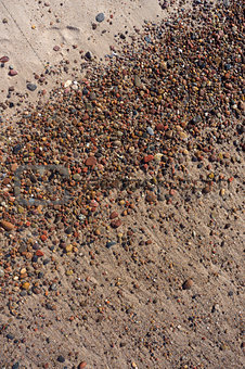Wet sand and pebbles on Baltic beach. Natural background.