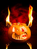 Evil face of Halloween pumpkin with flames and red smoke