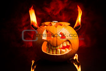 Evil face of Halloween pumpkin with flames and red smoke