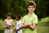 Portrait of boy and friends playing football in park 