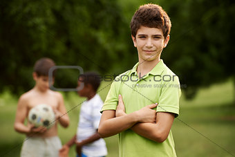 Portrait of boy and friends playing football in park 