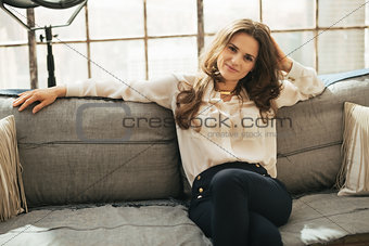 Relaxed young woman sitting in loft apartment