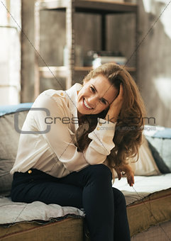 Portrait of smiling young woman sitting in loft apartment