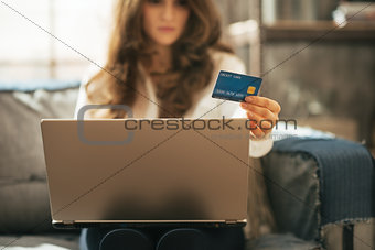 Closeup on young woman with credit card using laptop in loft apa