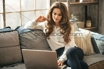 Young woman using laptop in loft apartment
