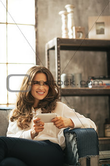 Happy young woman writing sms in loft apartment
