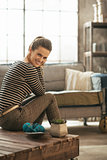 Smiling young woman sitting on coffee table in loft apartment