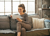 Smiling young woman using tablet pc in loft apartment