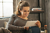 Happy young woman sitting on sofa and using tablet pc in loft ap
