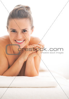 Portrait of happy young woman laying on massage table
