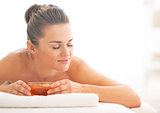 Young woman laying on massage table with honey plate
