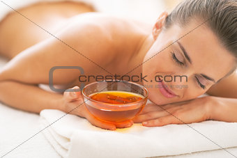 Relaxed young woman laying on massage table with honey plate