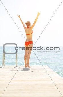 Young woman on bridge rejoicing. rear view