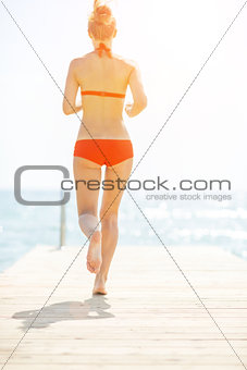 Young woman running on bridge. rear view