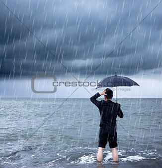 upset business man holding a umbrella with cloudburst background