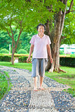 asian older woman walking on the stone walkway