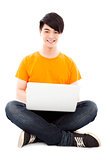 happy young student sitting on floor and  using laptop