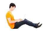 Happy young student sitting on floor and  using laptop