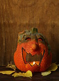 Halloween still life - pumpkin with  yellow leaves on the wooden background