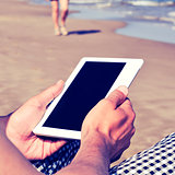 man using a tablet or an e-book on the beach