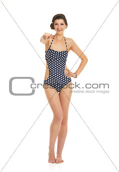 Full length portrait of happy young woman in swimsuit pointing i