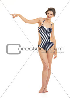 Full length portrait of happy young woman in swimsuit pointing o