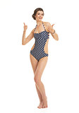 Full length portrait of smiling young woman in swimsuit showing 
